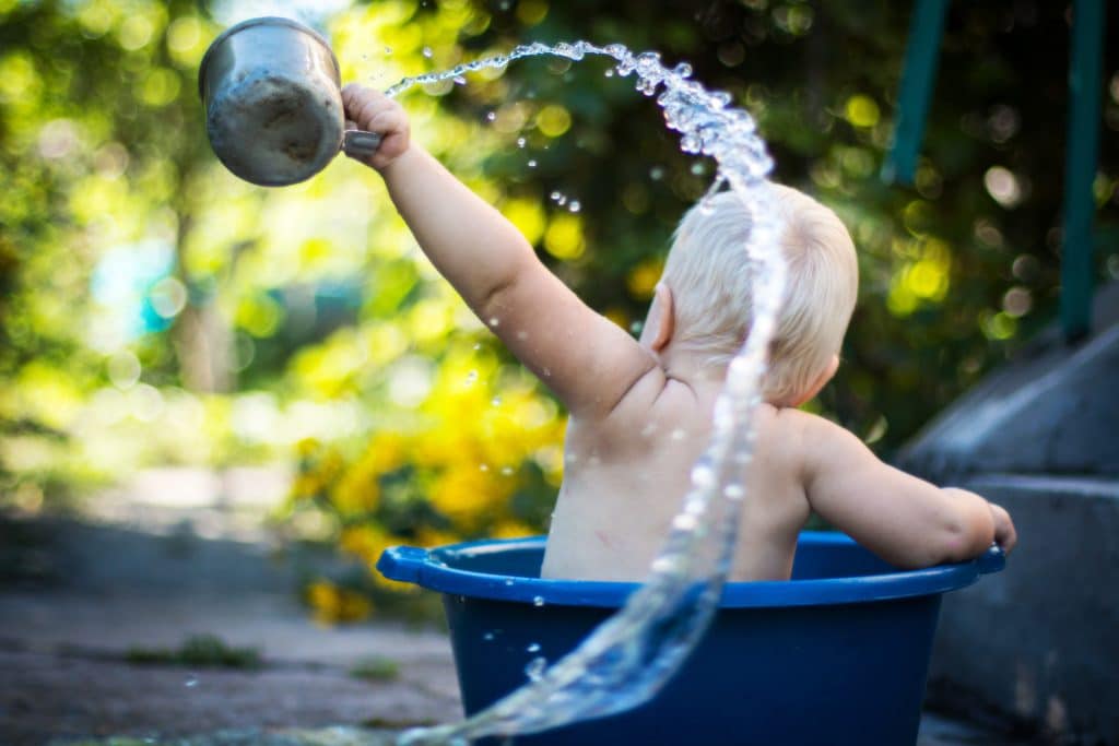 image of baby splashing in hot water bucket